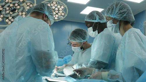 An international team of doctors performs a complex surgical operation on a patient under anesthesia. Modern operating room and experienced surgeons save lives