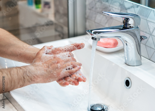 Man is washing handsMan is washing hands with soap and hot water at home bathroom sink. Guy is cleaning hands. Hygiene for coronavirus outbreak prevention. Co with soap. Coronavirus pandemic. Covid-19
