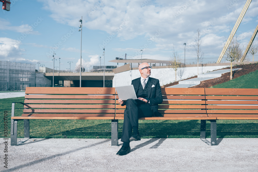 Adult businessman outdoor sitting bench using computer