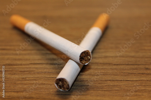 Two crossed cigarettes in wood table