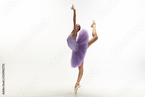 Graceful classic ballerina dancing, posing isolated on white studio background. Bright purple tutu. The grace, artist, movement, action and motion concept. Looks weightless, flexible. Fashion, style. photo