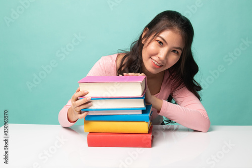 Happy young Asian woman read a book with books on table.