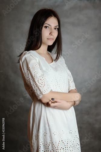 Portrait of a beautiful young brunette in whitee dress. photo