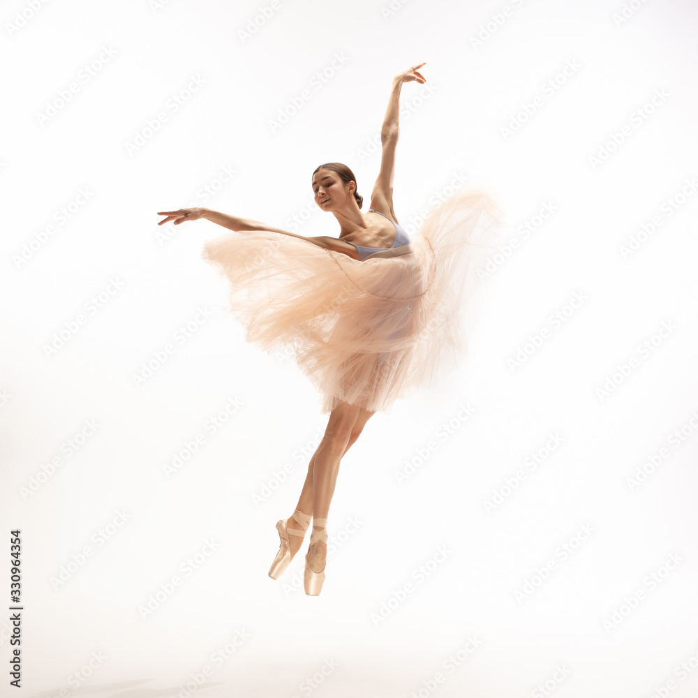 Fototapeta premium Graceful classic ballerina dancing, posing isolated on white studio background. Tender peach cloth. The grace, artist, movement, action and motion concept. Looks weightless, flexible. Fashion, style.
