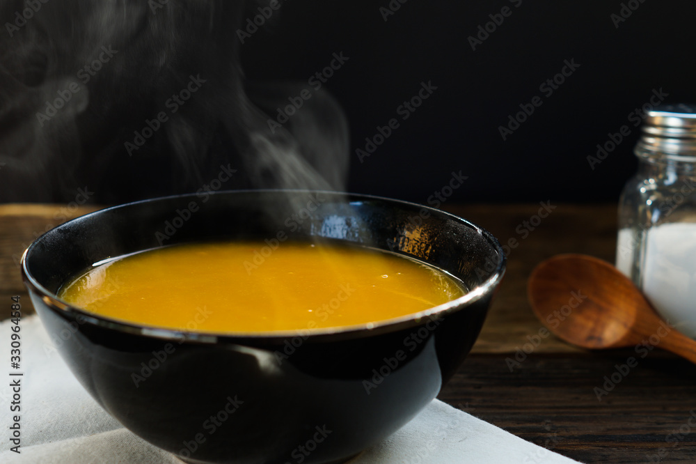 Steaming of hot pumkin soup in white bowl served on wooden table ready to eat. Hot food is good for healthy Steaming of hot pumkin soup in white bowl served on wooden table ready to eat. Hot food is good for healthy
