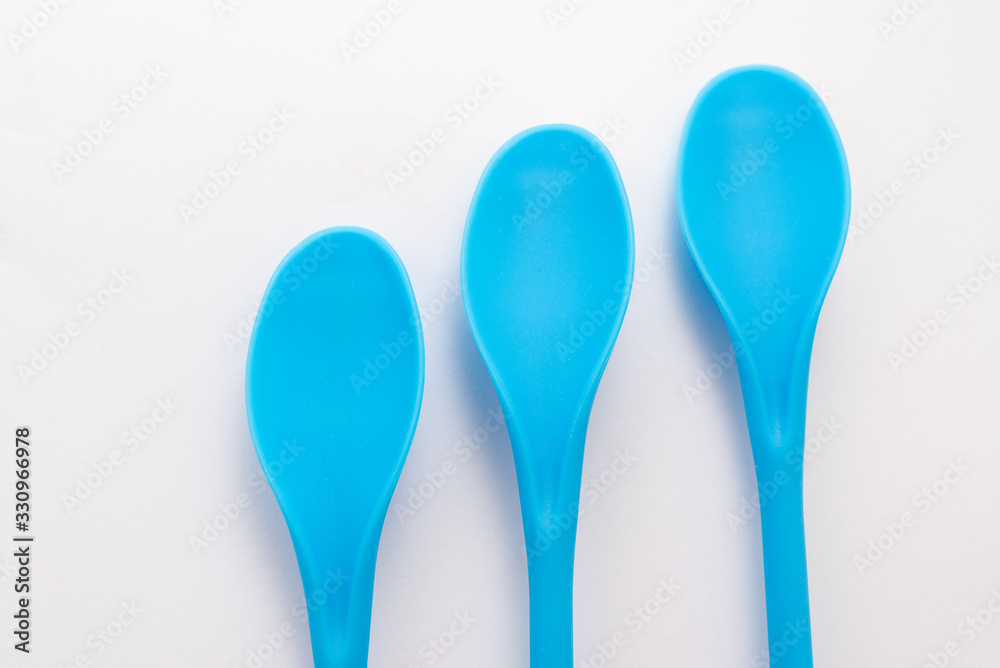 three blue kitchen plastic spoons on white background three blue kitchen plastic spoons on white background