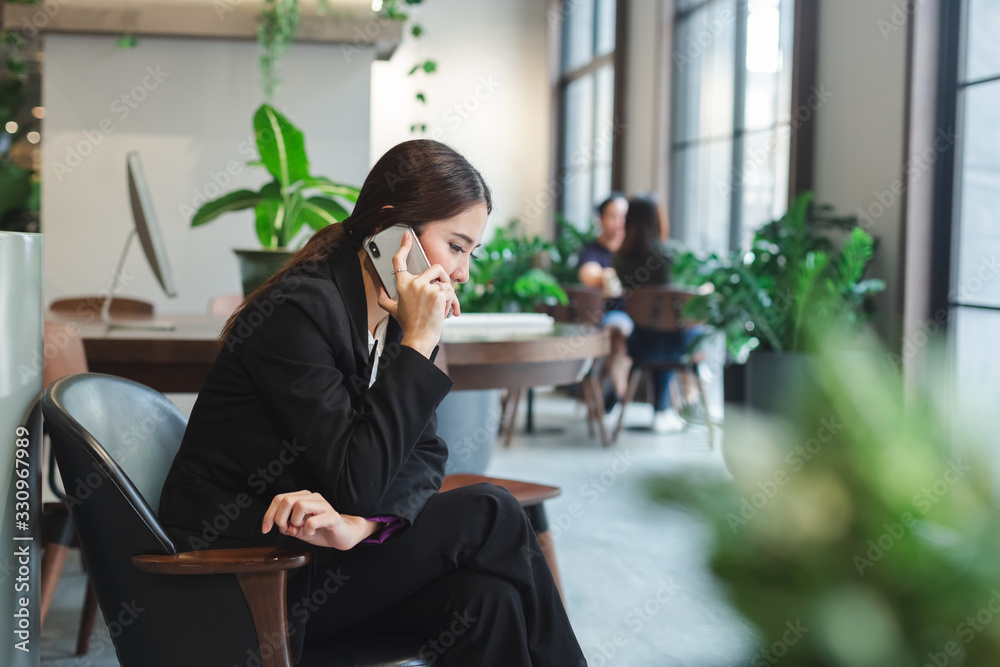 business woman in black suit talking mobile phone sitting in office spaces. business woman in black suit talking mobile phone sitting in office spaces.