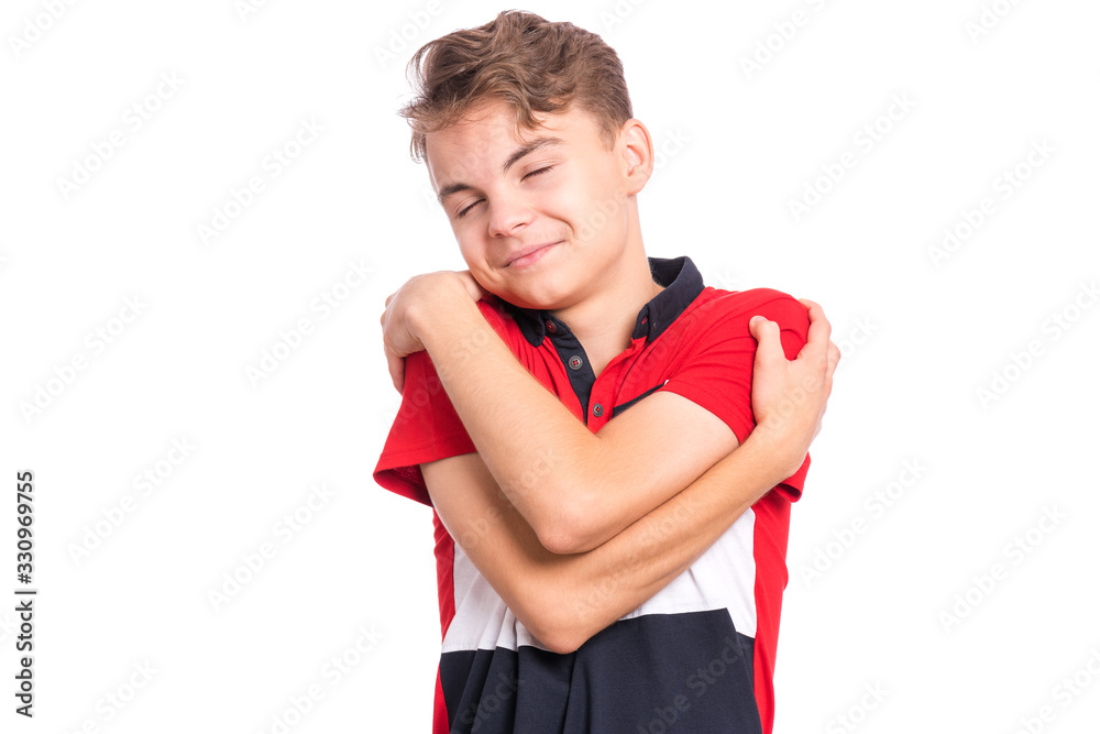 Self love and self care. Portrait of teen boy Hugging oneself, isolated on white background. Happy funny child. Cute caucasian young teenager smiling with eyes closed.