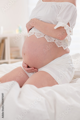 Close-up of the belly of a pregnant young woman at home.
