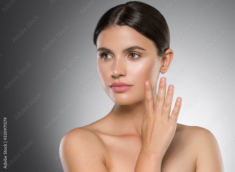 Woman portrait clean healthy skin with hand touching face over graybackground Woman portrait clean healthy skin with hand touching face over graybackground