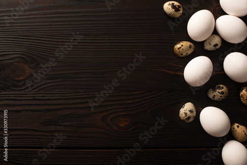 top view of chicken and quail eggs on dark wooden surface