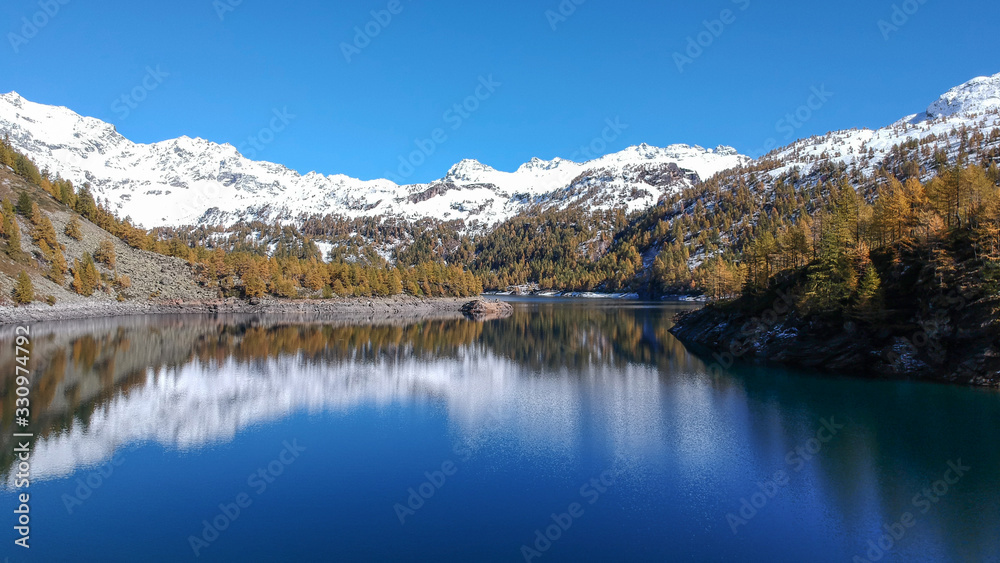 Italian Lake wtih snow-capped mountains and pine tree - Alpe Devero - Drone