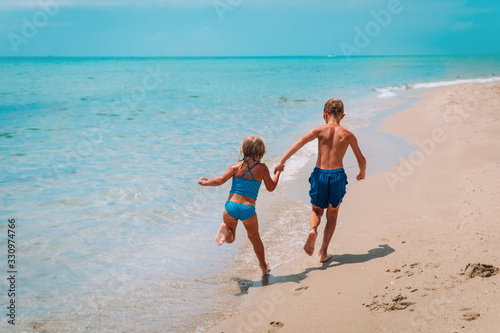 happy girl and boy run play with waves on beach © nadezhda1906