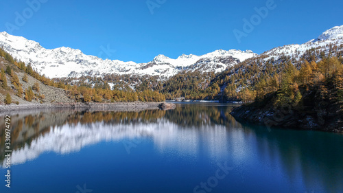 Italian Lake wtih snow-capped mountains and pine tree - Alpe Devero - Drone