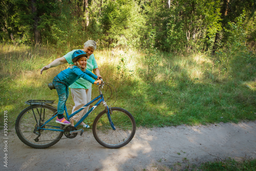 Obraz premium babcia uczy małą wnuczkę jeździć na rowerze