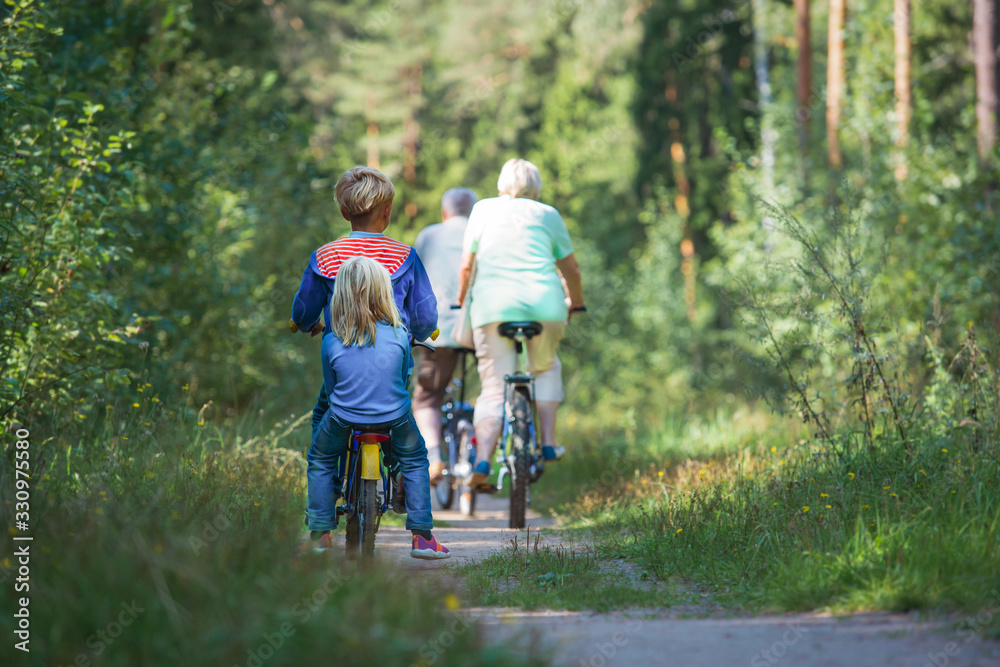 Obraz premium active senior couple with kids riding bikes in nature