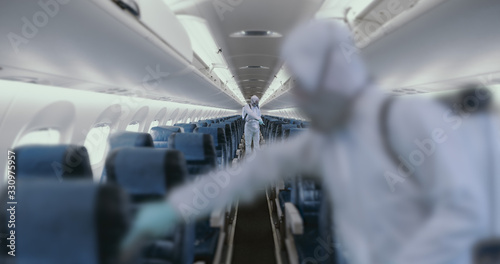 HazMat team in protective suits decontaminating airplane cabin during virus outbreak