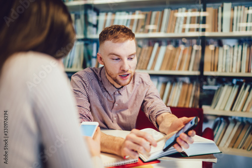 Colleagues chatting and browsing gadgets in library