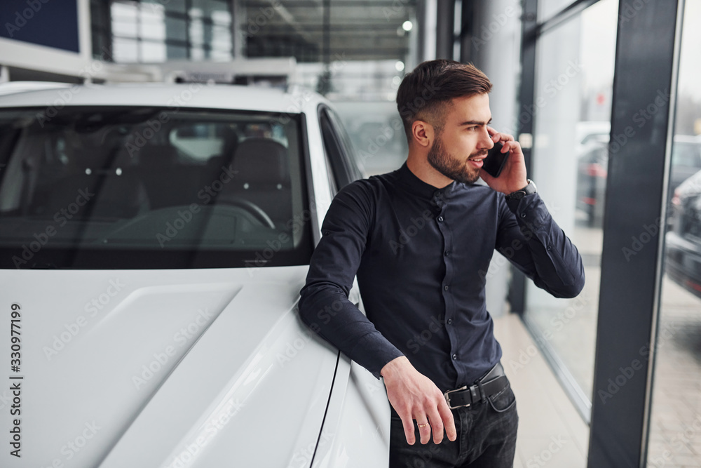 Young man in formal clothes is near brand new expensive car Young man in formal clothes is near brand new expensive car