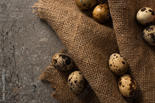 top view of quail eggs on sackcloth on grey concrete background