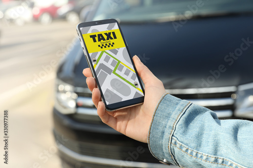 Woman ordering taxi with smartphone on city street, closeup