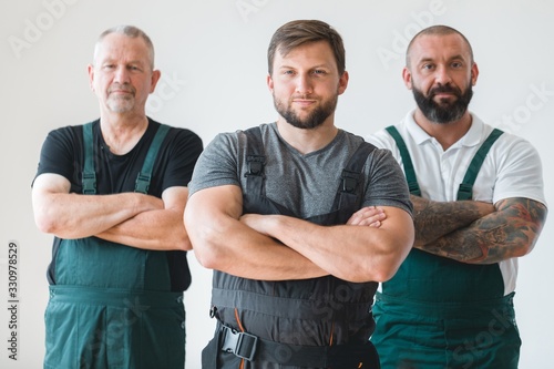 Crew of three professional builder wearing overalls standing in empty interior photo