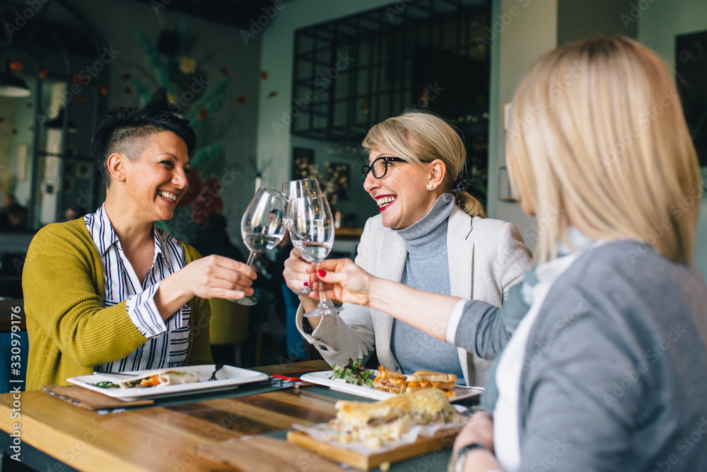 women friends making toast with wine in restaurant