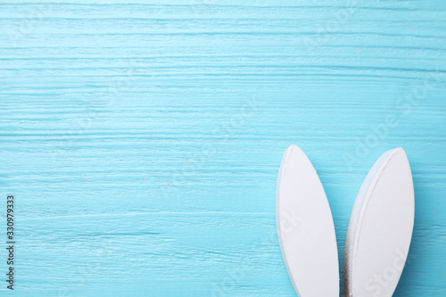 Decorative bunny ears and space for text on light blue wooden background, flat lay. Easter holiday