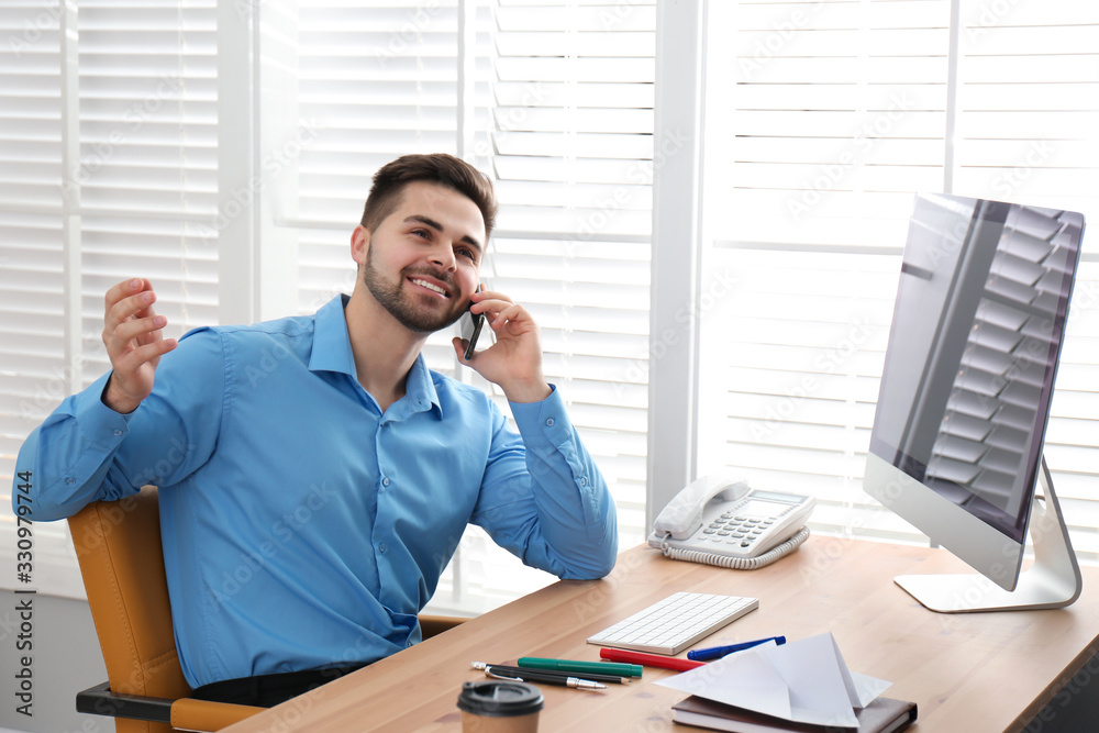 Lazy employee talking on smartphone at table in office Lazy employee talking on smartphone at table in office