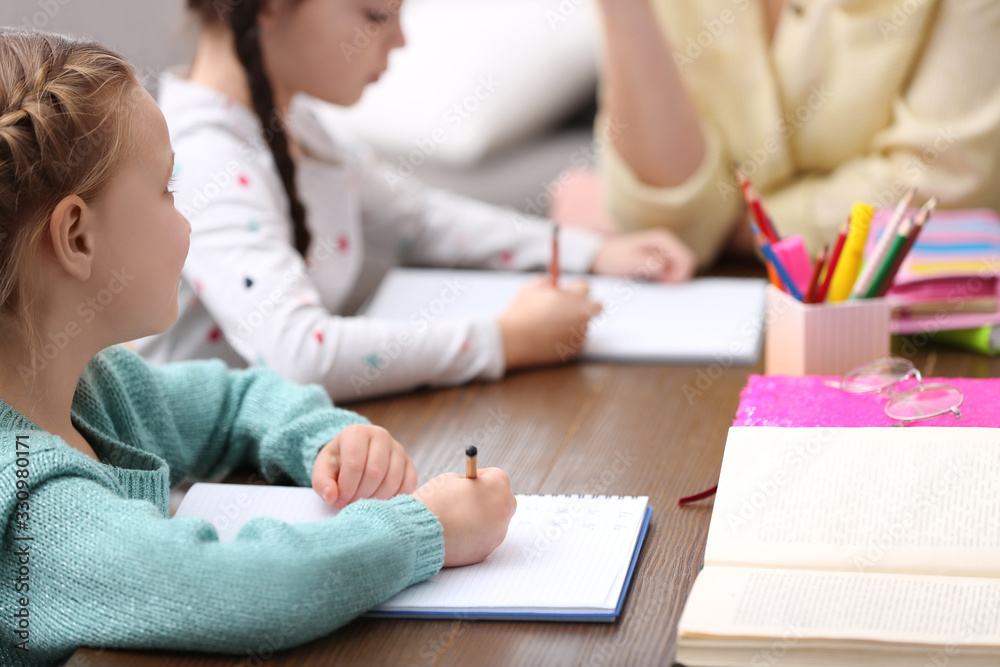 Little girls doing homework with mother at table Little girls doing homework with mother at table