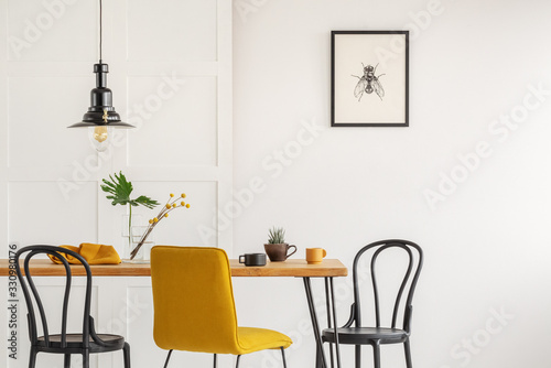 Stylish yellow chair at wooden dining table in trendy interior photo