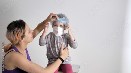 Mom and daughter in protective mask are fooling around, having fun, rejoicing. Inflatable protective rubber gloves. Child in a medical mask. Epidemic situation. Novel coronavirus (2019-nCoV).