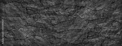 Cracked stone surface. Close-up. Black abstract grunge background. Banner with black rock texture. Copy space.