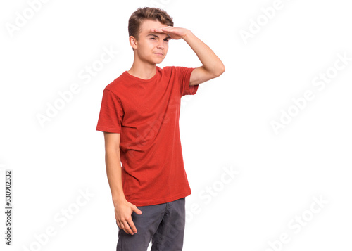 Portrait of serious teen boy looking far away with hand over head. Searching concept. Beautiful child holding hand at forehead looking far away distance, isolated on white background.