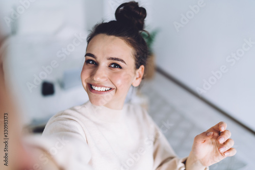 Positive young woman using smartphone and having entertainment at home photo