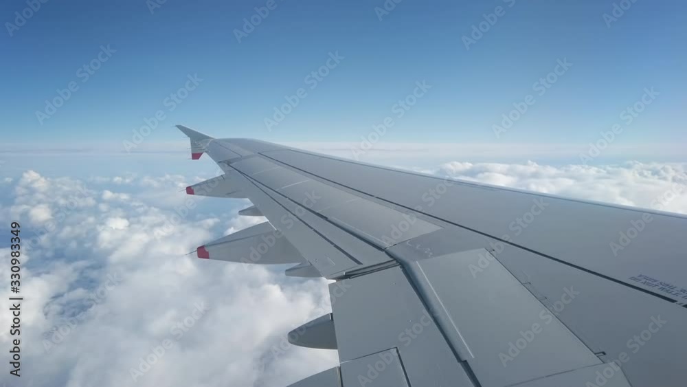 Flying over white clouds, view from passenger jet porthole of aircraft wing, and blue sky. Flying over white clouds, view from passenger jet porthole of aircraft wing, and blue sky.