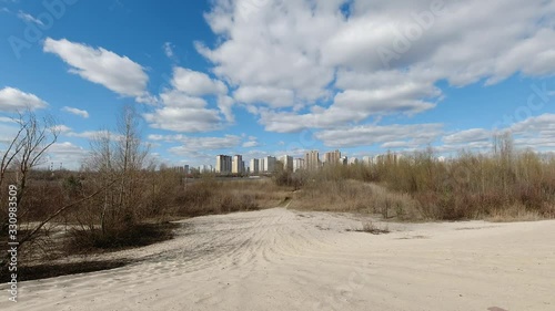 Early spring landscape of sand desert with city view on the horizon and fast moving clouds on blue sky 4k timelapse photo