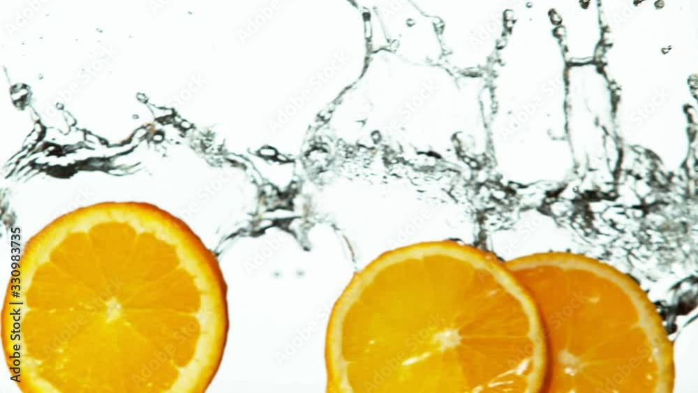 Super slow motion of orange slices with water splash on white background. Filmed on high speed cinema camera, 1000 fps.