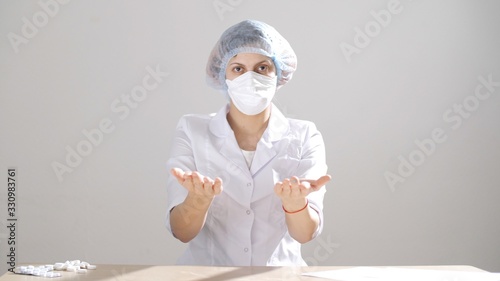  Girl doctor in a medical protective mask pours tablets from hand to hand and loocking at camera. Novel coronavirus (2019-nCoV). photo