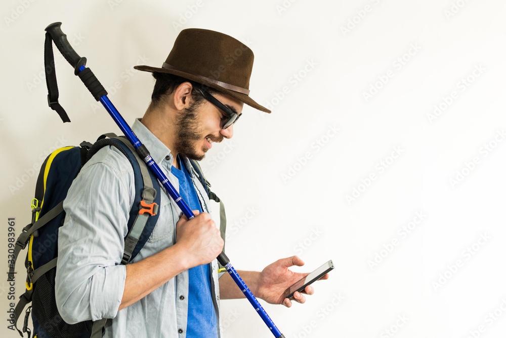 young tourist with hat, glasses, backpack, trekking pole, look at his mobile. young tourist with hat, glasses, backpack, trekking pole, look at his mobile.