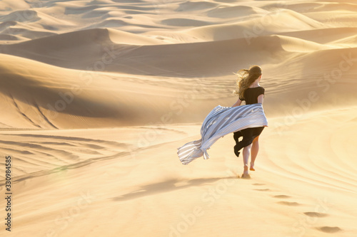 Caucasian young beautiful girl alone is in a hot  waterless desert Runs along the sandy mountains and dunes.