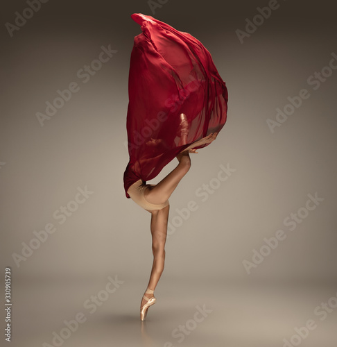 Pouring wine. Graceful classic ballerina dancing on grey studio background. Tender red cloth. The grace, artist, movement, action and motion concept. Looks weightless, flexible. Fashion, style.