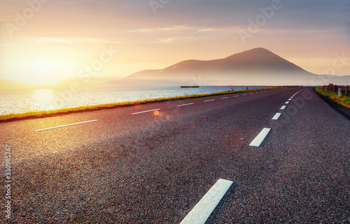Fototapeta Naklejka Na Ścianę i Meble -  Asphalt road along the sea at sunset