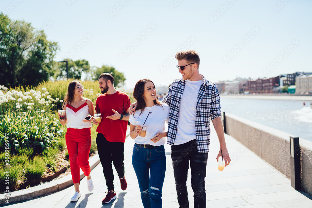 Couple walking in am embrace with casual friends and chatting at quay