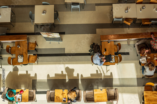 Top view of the cafeteria, where people sit at each table, eat, dine and do business. Horizontal view.