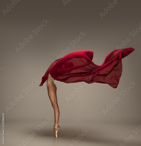 Fototapeta Naklejka Na Ścianę i Meble -  Passioned in motion. Graceful classic ballerina dancing on grey studio background. Deep red cloth. The grace, artist, movement, action and motion concept. Looks weightless, flexible. Fashion, style.