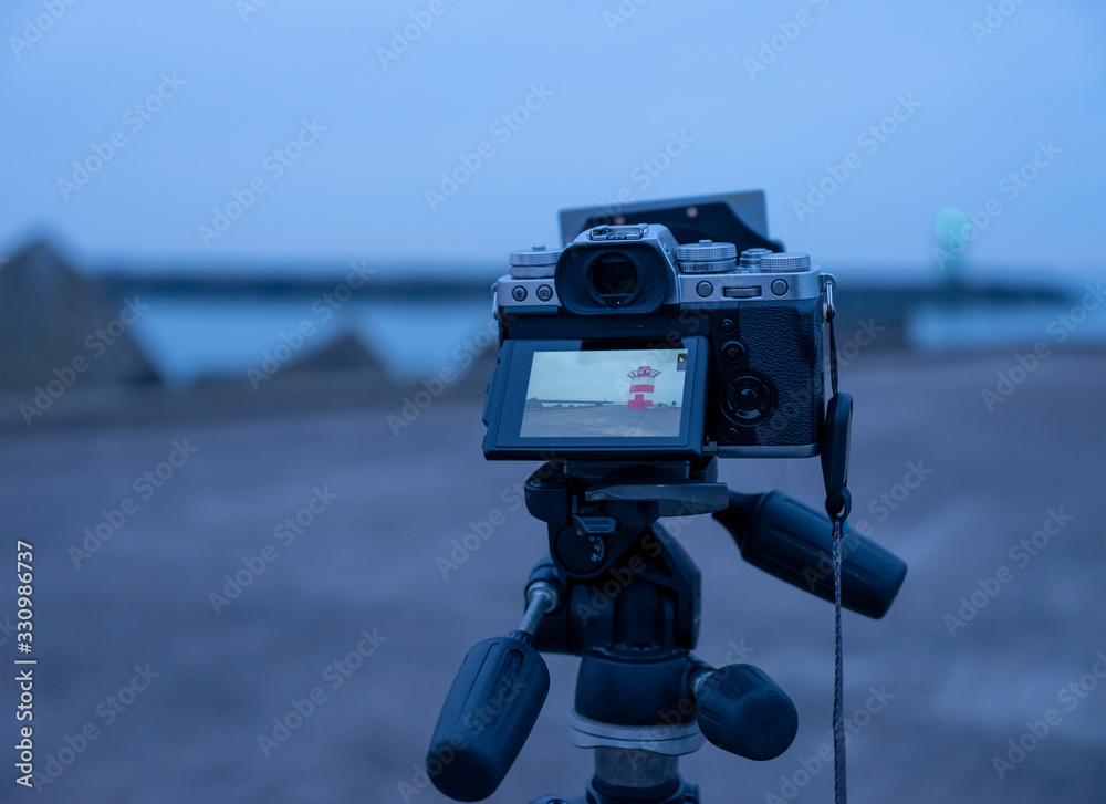 A system camera on a tripod with ND filter on it, during the blue hour on the pier of Scheveningen, on the background blue Sea and sky, Scheveningen, The Hetherlands