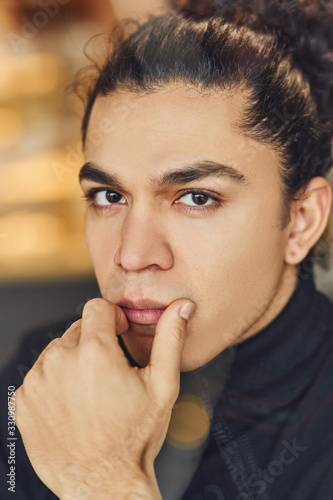 Portrait of confident young man in black sweater that sitting indoors