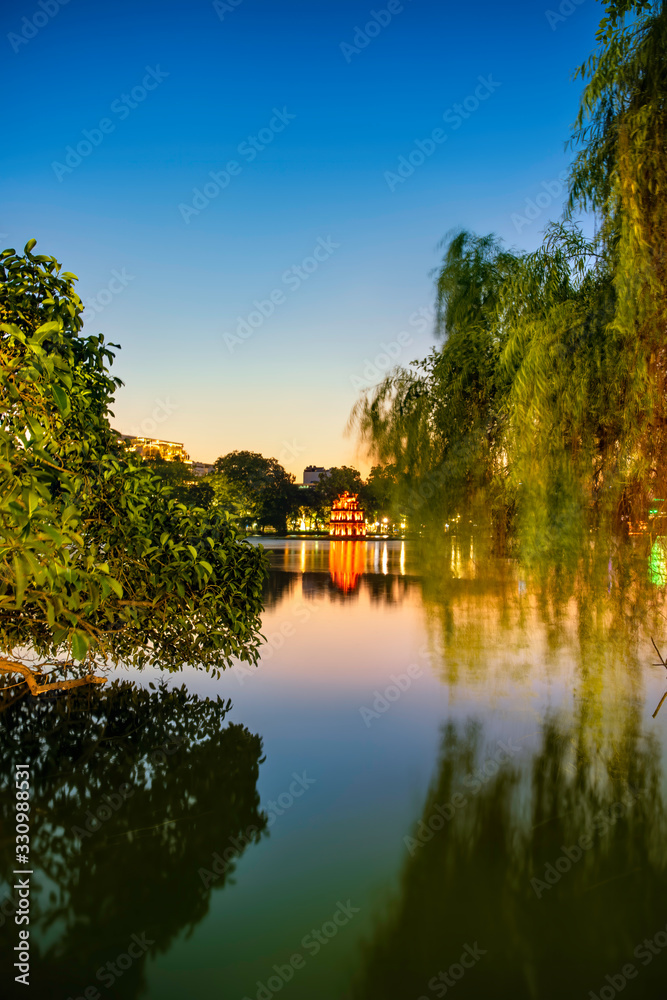 Turtle Tower in the center of Hoan Kiem Lake(Lake of the Returned Sword) framed by trees. This tower is a popular tourist attraction in Hanoi, Vietnam