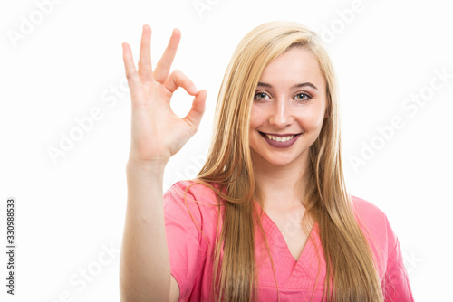 Portrait of young female nurse wearing scrubs showing ok gesture